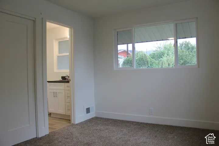 Neutral-toned wall-to-wall carpeting, horizontal sliding window with white trim, and white solid-core interior door
