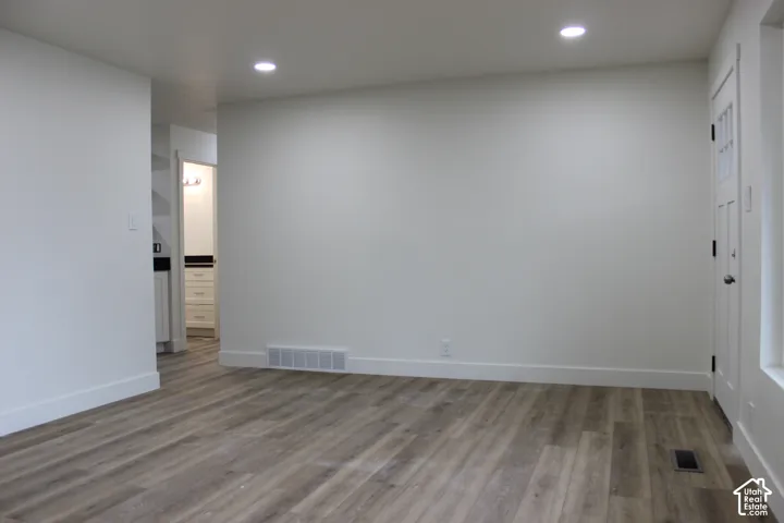 Interior space featuring neutral wall paint, wood-finish flooring, and recessed ceiling lighting