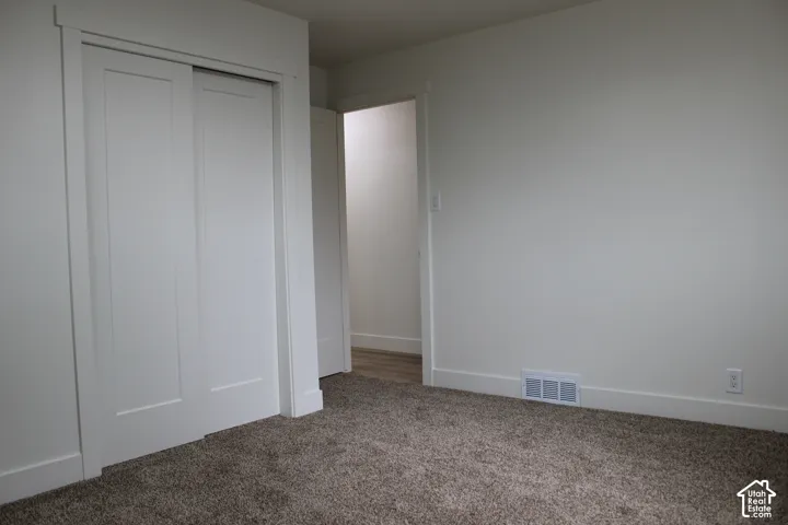 Neutral-toned carpeted flooring, white two-panel sliding closet doors, and interior trim with matching door casings