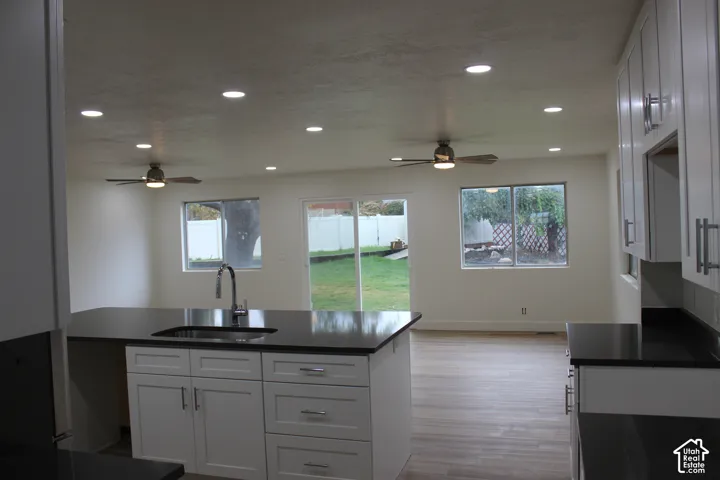 Kitchen featuring white shaker-style cabinetry, dark solid-surface countertops, wood-finish flooring, recessed lighting, and dual ceiling fans