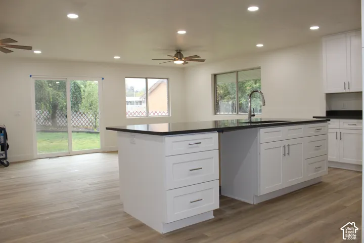Kitchen featuring a center island with a dark countertop, white cabinetry, recessed lighting, wood-finish flooring, and sliding glass doors