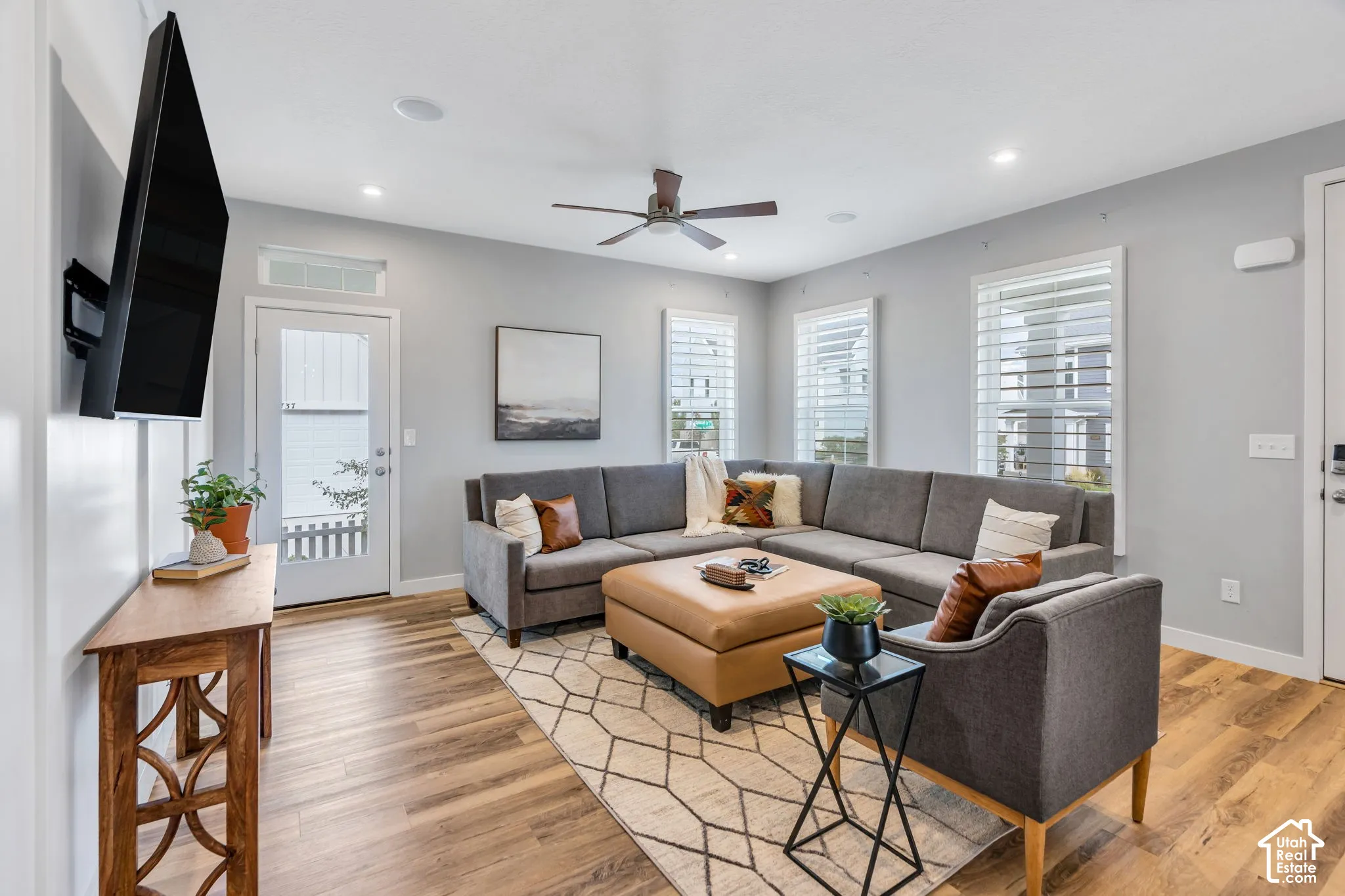 Open-concept area featuring wood-finish flooring, recessed lighting, a ceiling fan, and shutters