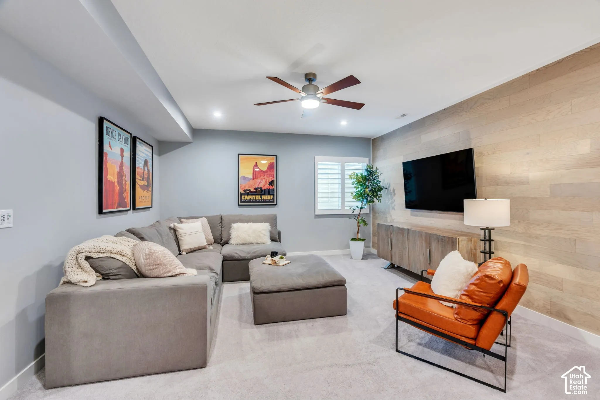 Accent wall featuring horizontal wood-finish planks, recessed ceiling lighting, multi-blade ceiling fan, and window shutters