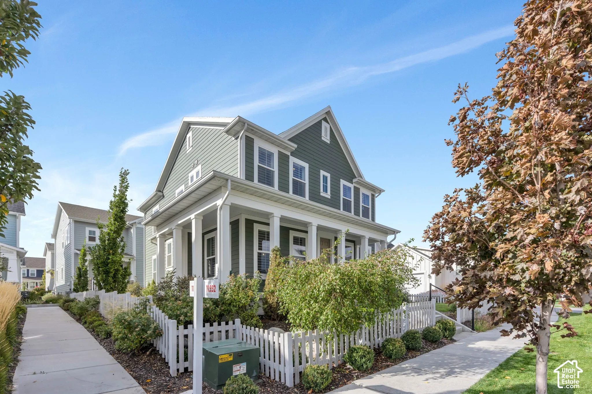 Two-story exterior with horizontal siding, a gabled roofline, a front porch featuring square columns, and a perimeter picket fence