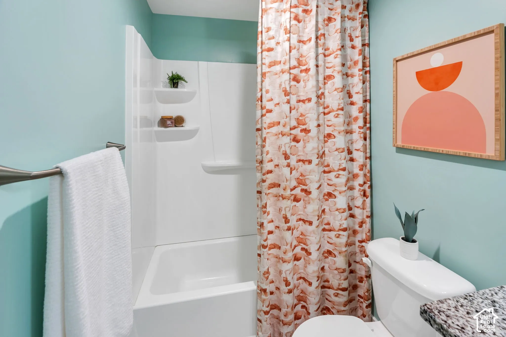 Bathroom featuring a white acrylic bathtub and shower surround with integrated shelving, a brushed nickel towel bar, and a stone-finish countertop