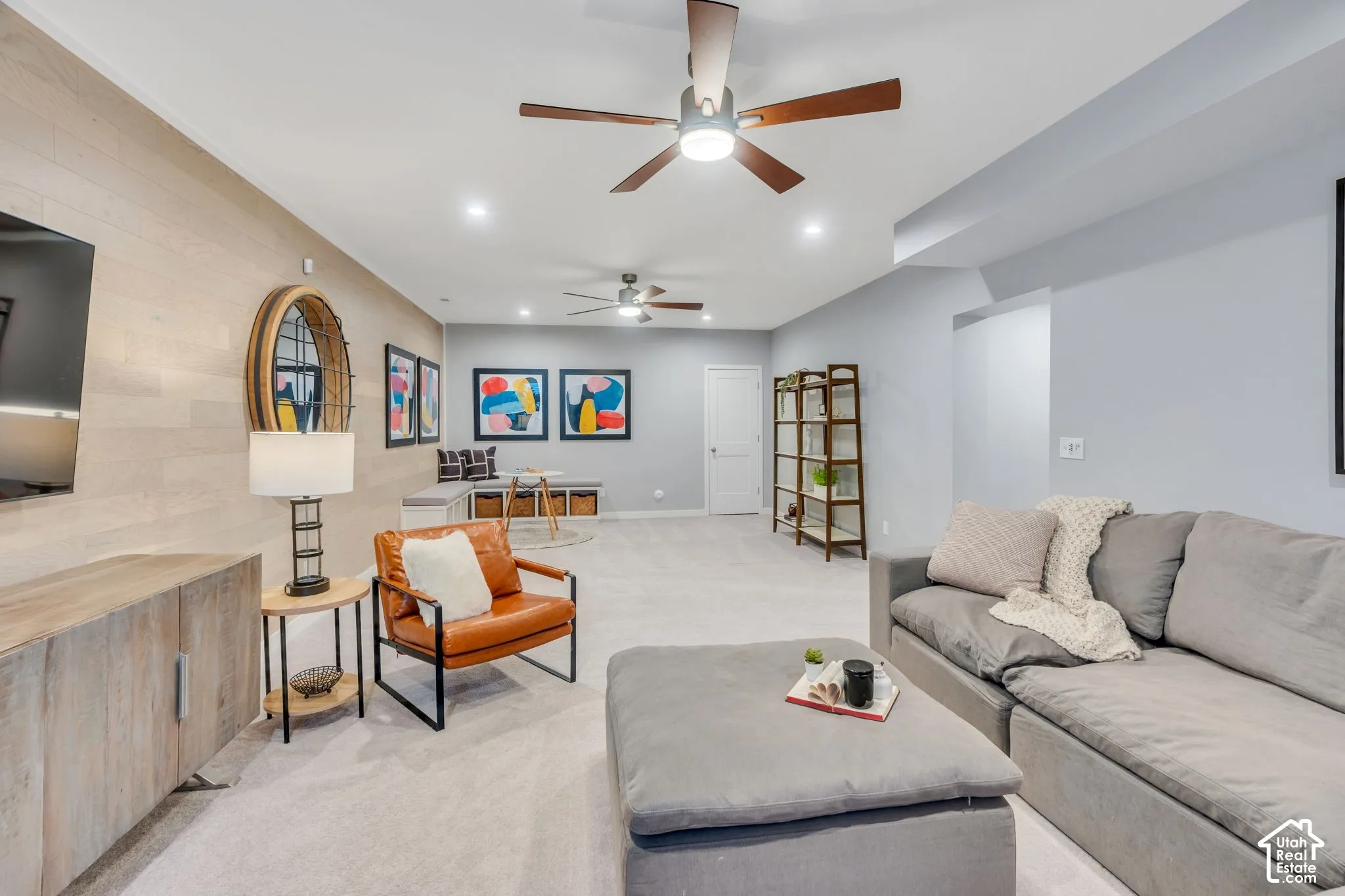 Light-toned wood-plank wall accent, two ceiling fans with integrated lighting, recessed lighting, and neutral carpeting