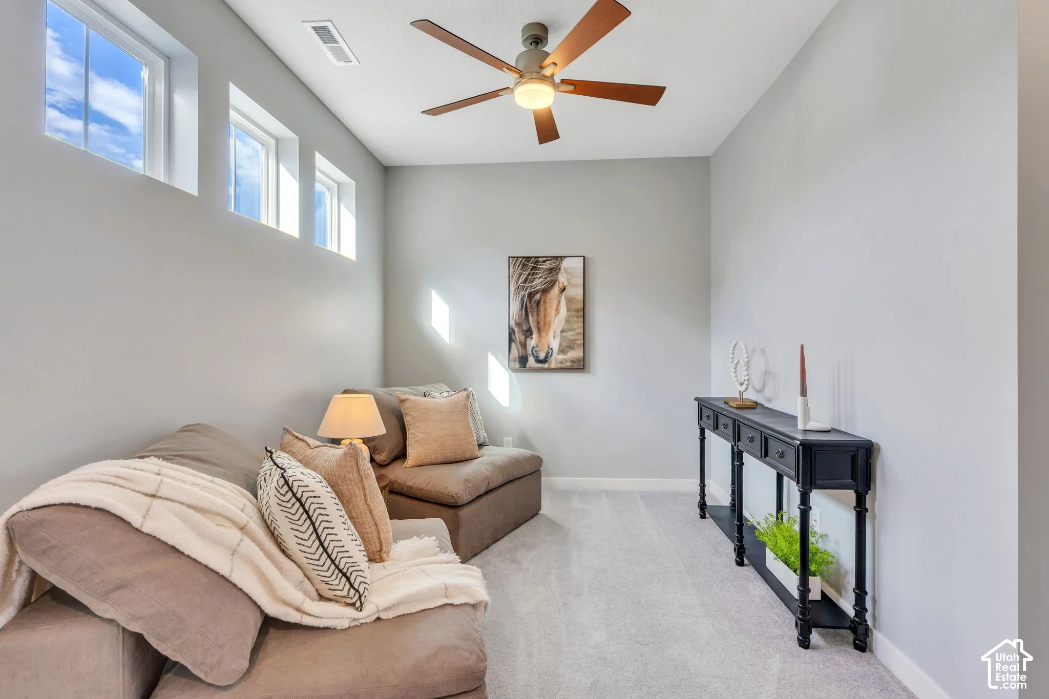 Room featuring a high ceiling, three transom windows, and a central ceiling fan with an integrated light fixture