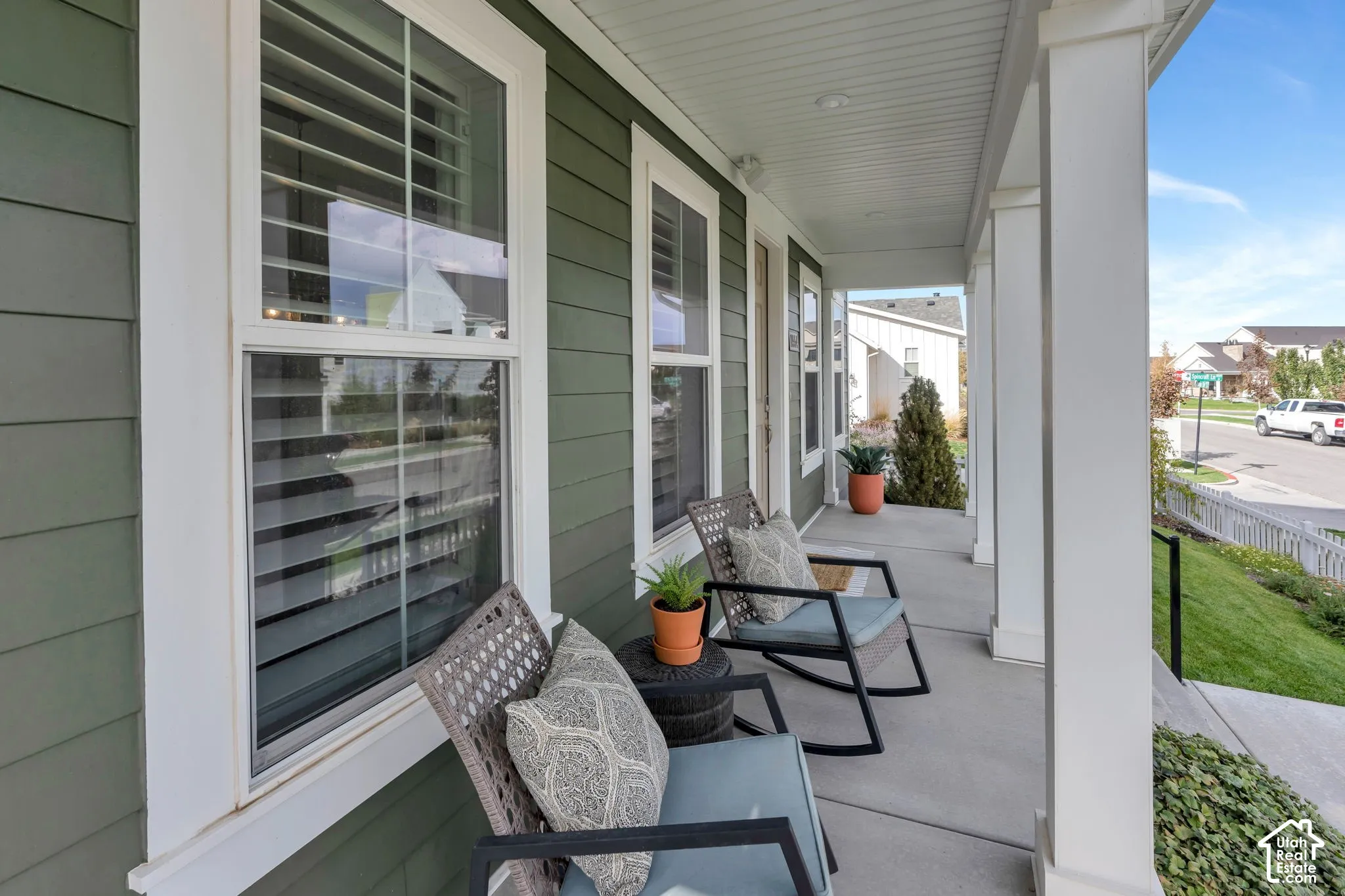 Covered front porch featuring horizontal lap siding, square support columns, recessed ceiling lighting, and crisp white window trim