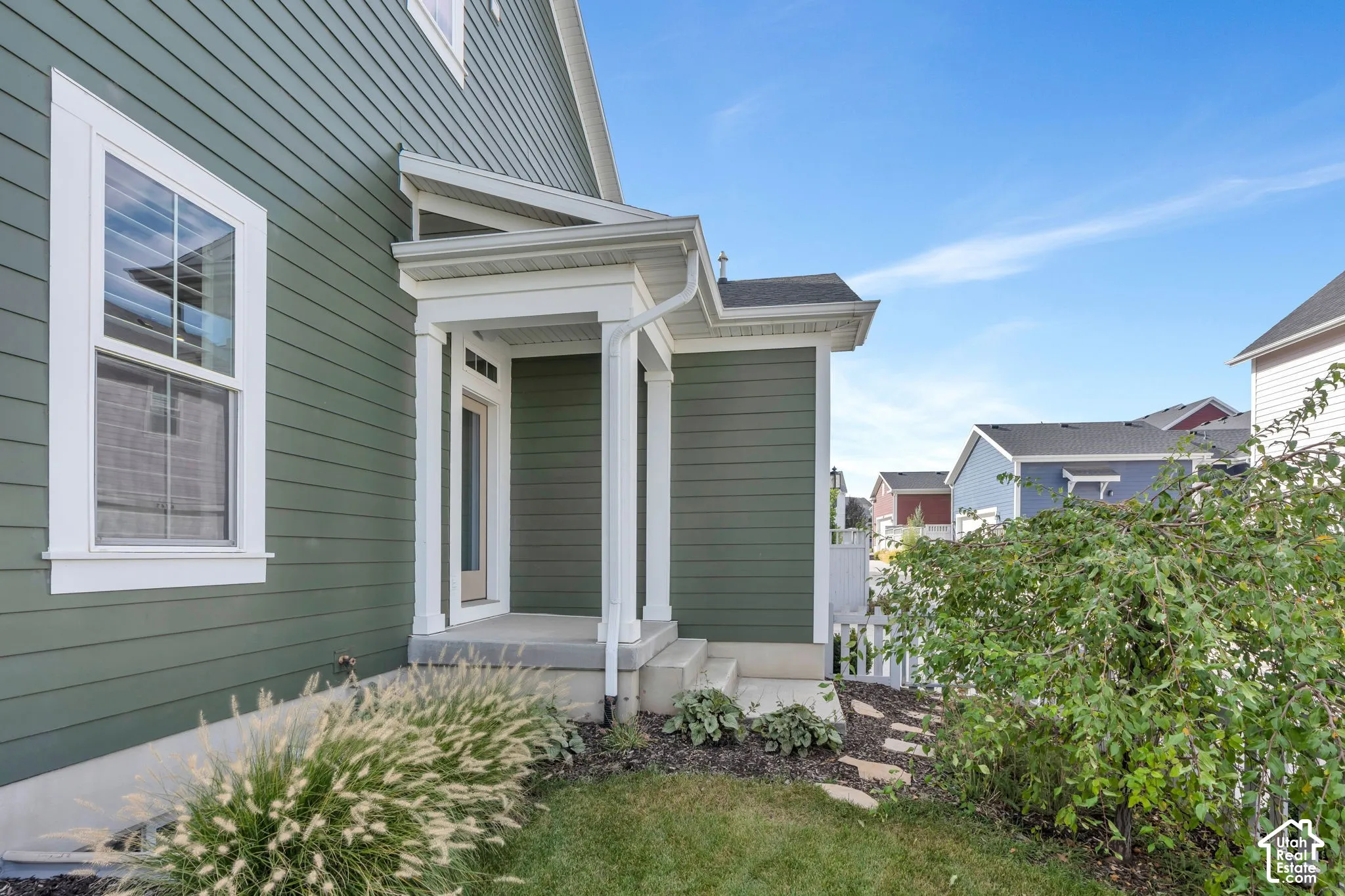 Exterior featuring olive-toned horizontal siding, a covered entry with structural columns, concrete porch steps, and white trim accents