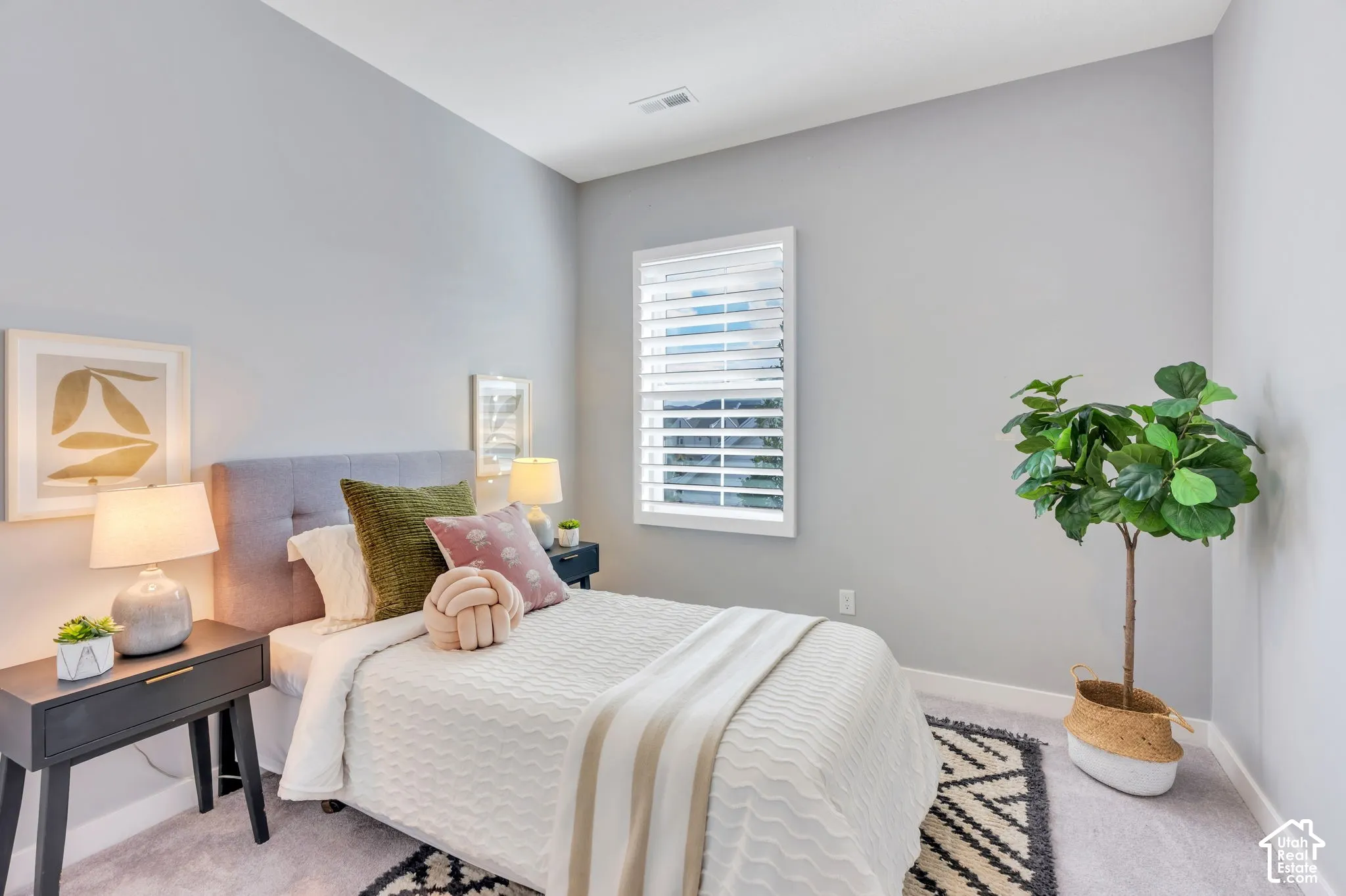 Neutral-toned walls paired with plush carpeting and a window featuring adjustable white plantation shutters
