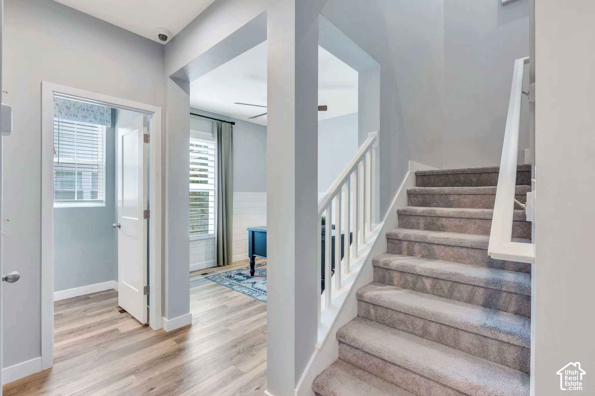 Staircase with white railing, wood-finish flooring, interior door, and shiplap wall accents