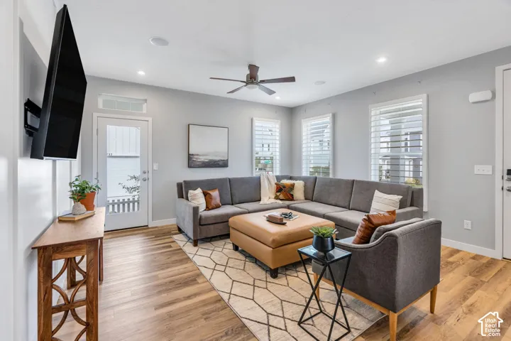 Open-concept area featuring wood-finish flooring, recessed lighting, a ceiling fan, and shutters