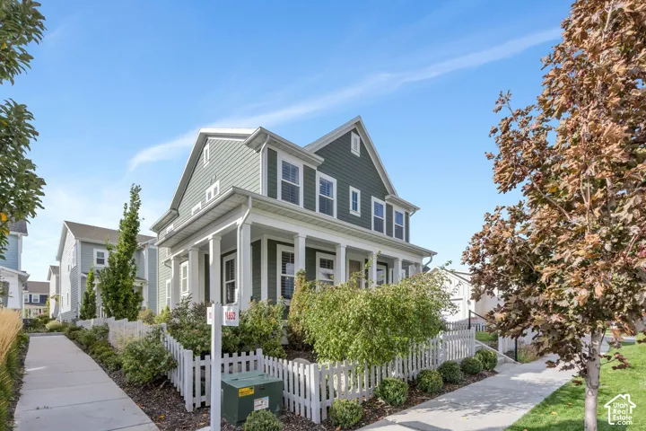 Two-story exterior with horizontal siding, a gabled roofline, a front porch featuring square columns, and a perimeter picket fence