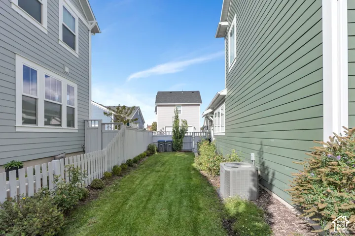 Exterior side yard featuring horizontal lap siding, a white picket fence, manicured grass lawn, and low-maintenance landscaping