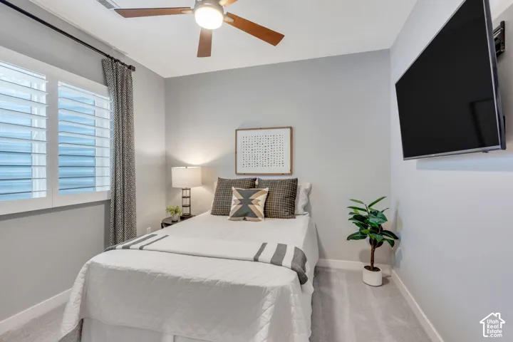 Bedroom interior featuring wall-to-wall carpeting, plantation shutters, and a ceiling fan with integrated lighting