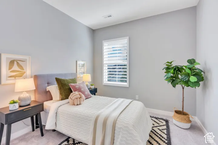 Neutral-toned walls paired with plush carpeting and a window featuring adjustable white plantation shutters