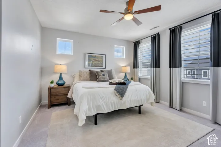 Neutral interior space featuring neutral wall paint, carpeting, a ceiling fan, and large windows with integrated blinds