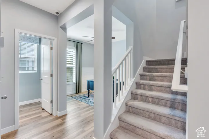 Staircase with white railing, wood-finish flooring, interior door, and shiplap wall accents