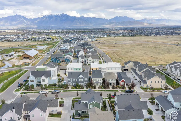 Aerial perspective of a planned community featuring multi-story residential architecture, paved thoroughfares, manicured landscaping, and mountain backdrops