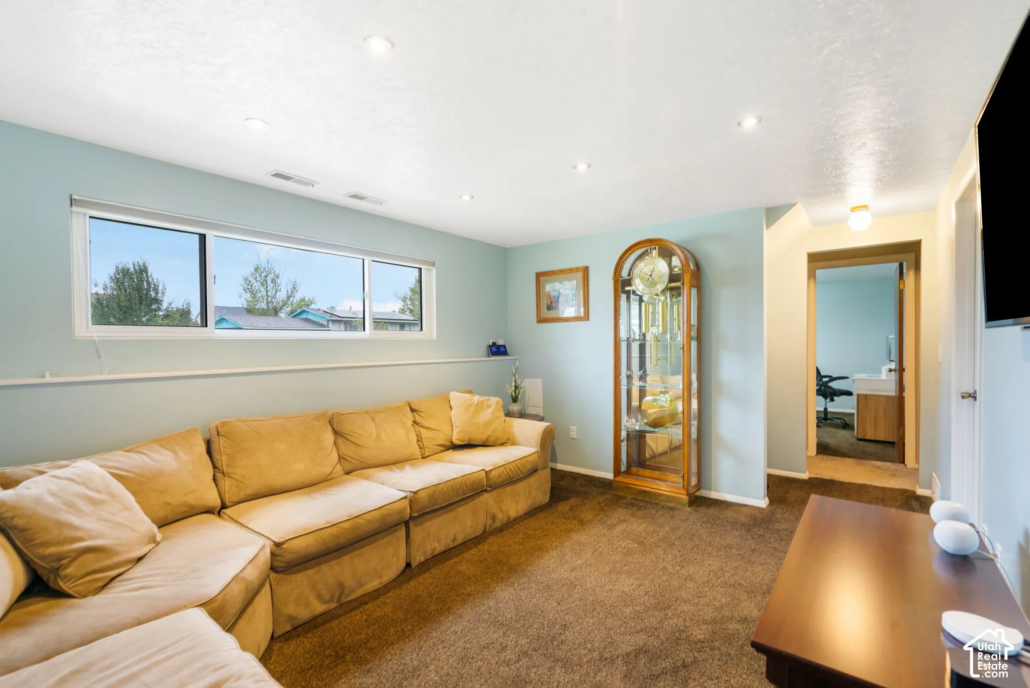 Living area featuring wall-to-wall carpeting, recessed ceiling lighting, and a large horizontal sliding window