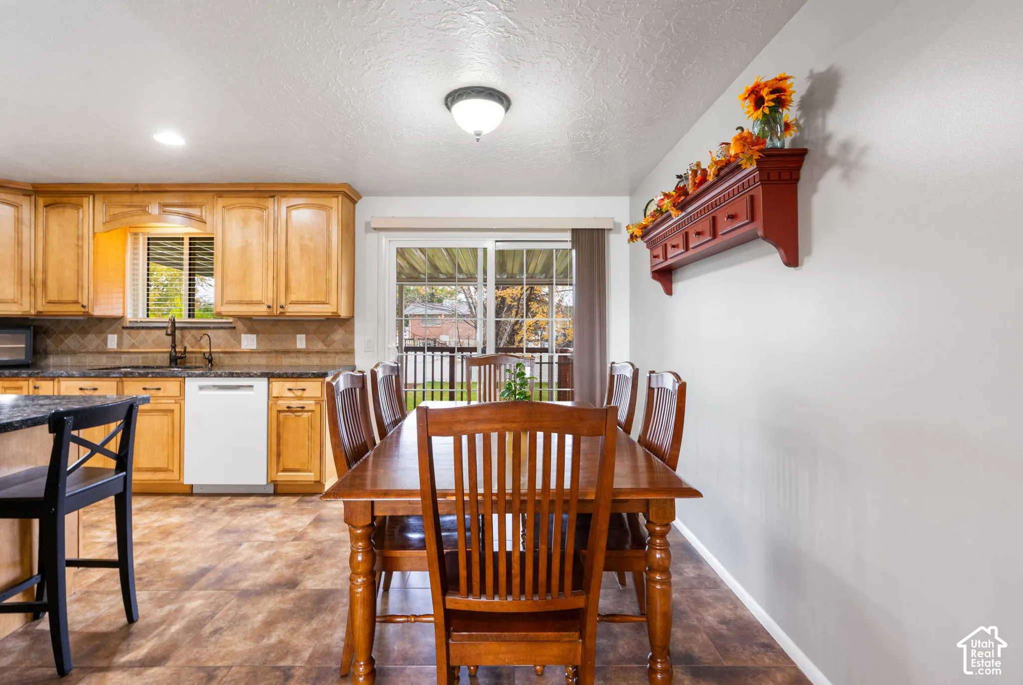 Kitchen featuring natural wood cabinetry, stone-finish countertops, tile backsplash, flush-mount lighting, and sliding glass patio doors