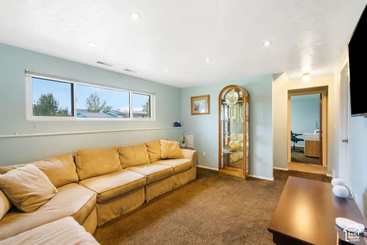 Living area featuring wall-to-wall carpeting, recessed ceiling lighting, and a large horizontal sliding window
