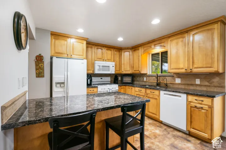 Kitchen featuring wood cabinetry, stone-surface countertops, tile backsplash, built-in appliances, and recessed lighting