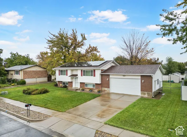 Split-level exterior featuring brick and siding facade, concrete driveway, two-car garage, and rooftop solar panels