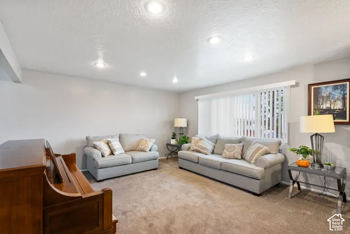 Living area featuring recessed lighting, wall-to-wall carpeting, and a large window with vertical blinds