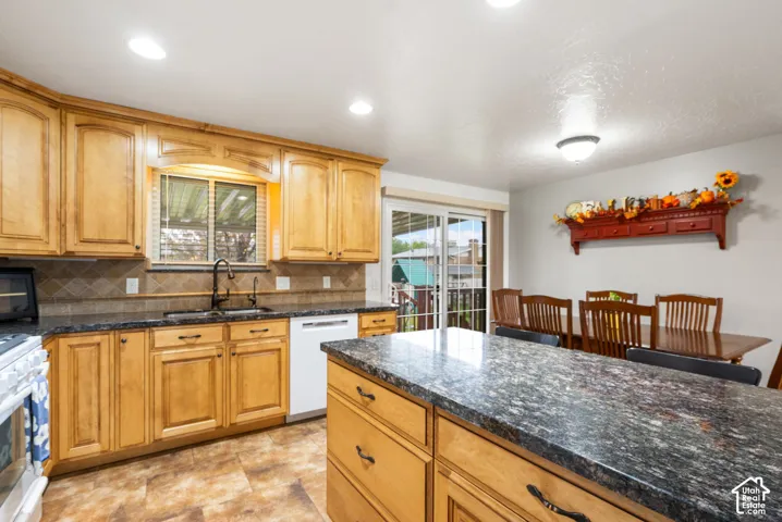 Kitchen featuring natural wood cabinetry, stone-finish countertops, tile backsplash, center island, and recessed lighting