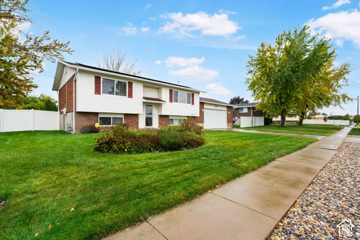 Split-level exterior featuring brick and horizontal siding, an attached two-car garage, and landscaped shrubbery
