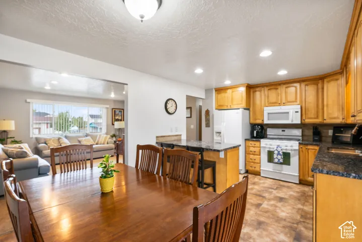 Kitchen area featuring wood cabinetry, stone-finish countertops, built-in microwave, and recessed lighting