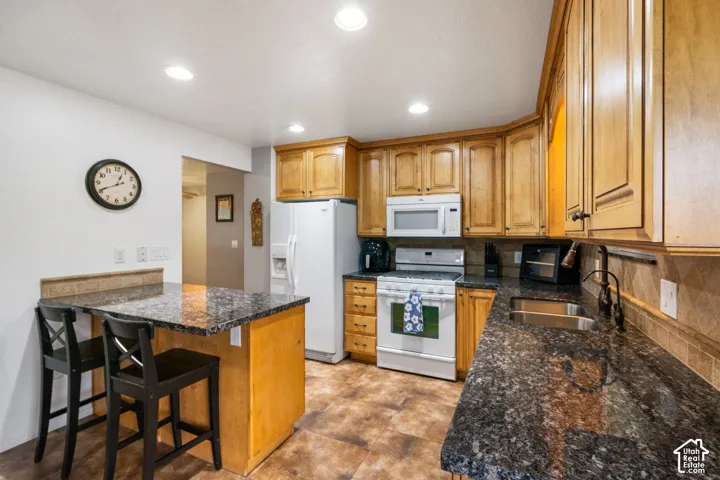 Kitchen featuring wood cabinetry, stone countertops, an integrated breakfast bar, recessed lighting, and tile flooring