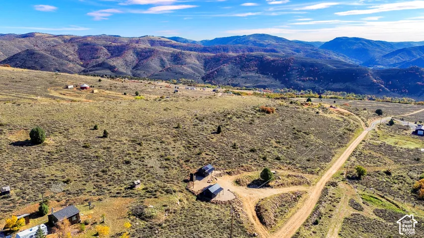Expansive undeveloped land featuring a dirt road and scattered natural vegetation with a mountainous backdrop