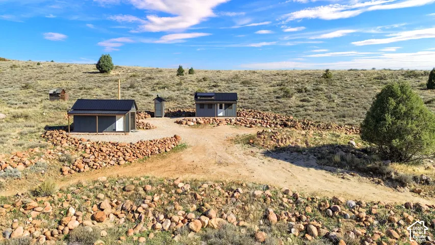 Multiple structures with dark metal roofs, set on a gravel-covered area