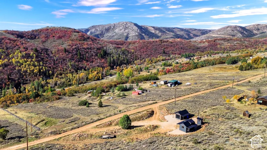 Mountain landscape with extensive natural terrain, featuring multiple structures and a dirt road network