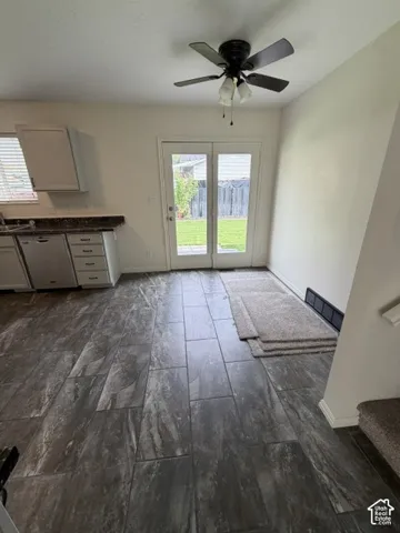 Kitchen featuring cabinetry with stone-surface countertops, stainless steel dishwasher, tile flooring, and glass-paneled double doors