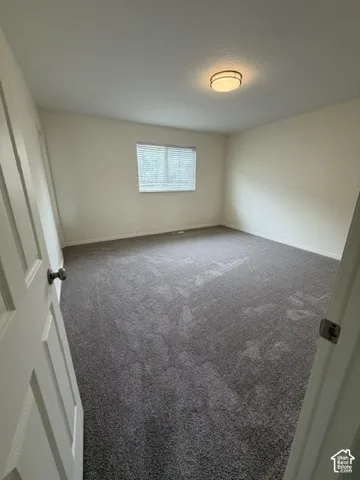 Master bedroom Neutral-toned interior room featuring wall-to-wall carpeting, a flush-mount ceiling light fixture, and a window with horizontal blinds