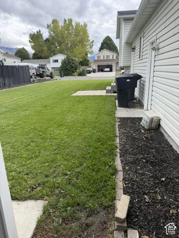 Back yard featuring a grass lawn, paved patio area, and stone-bordered landscaping beds with mulch finish