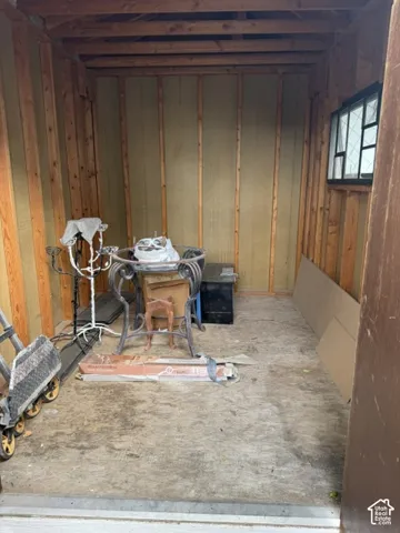 Detached storage structure with exposed wood framing, wood-composite flooring, and a multi-pane window