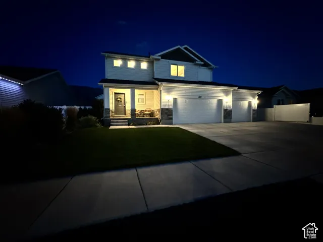 Two-story exterior featuring horizontal siding, stone veneer accents, a covered front porch, and a three-car garage