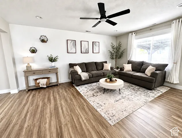 Living area featuring wood-finish flooring, recessed lighting, and a matte black ceiling fan
