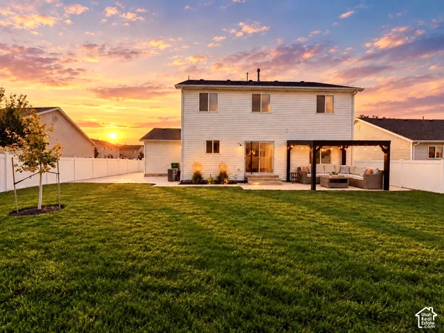 Expansive backyard featuring a manicured lawn, full-perimeter vinyl fencing, concrete patio, and a pergola structure