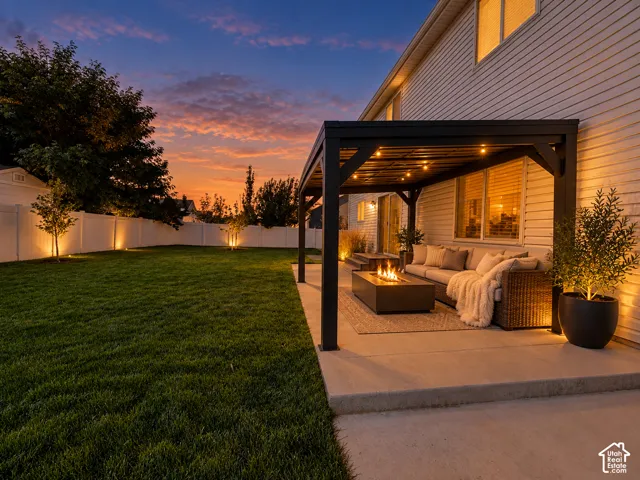 Backyard featuring a concrete patio, a metal-frame pergola with integrated lighting, and a perimeter vinyl privacy fence