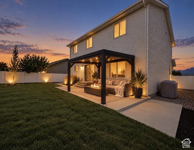 Rear exterior featuring vinyl siding, a covered concrete patio with a dark metal pergola, and a fenced backyard with a manicured lawn