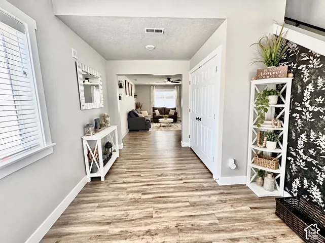 Entryway featuring wood-finish flooring, a double-door closet, and a patterned accent wall