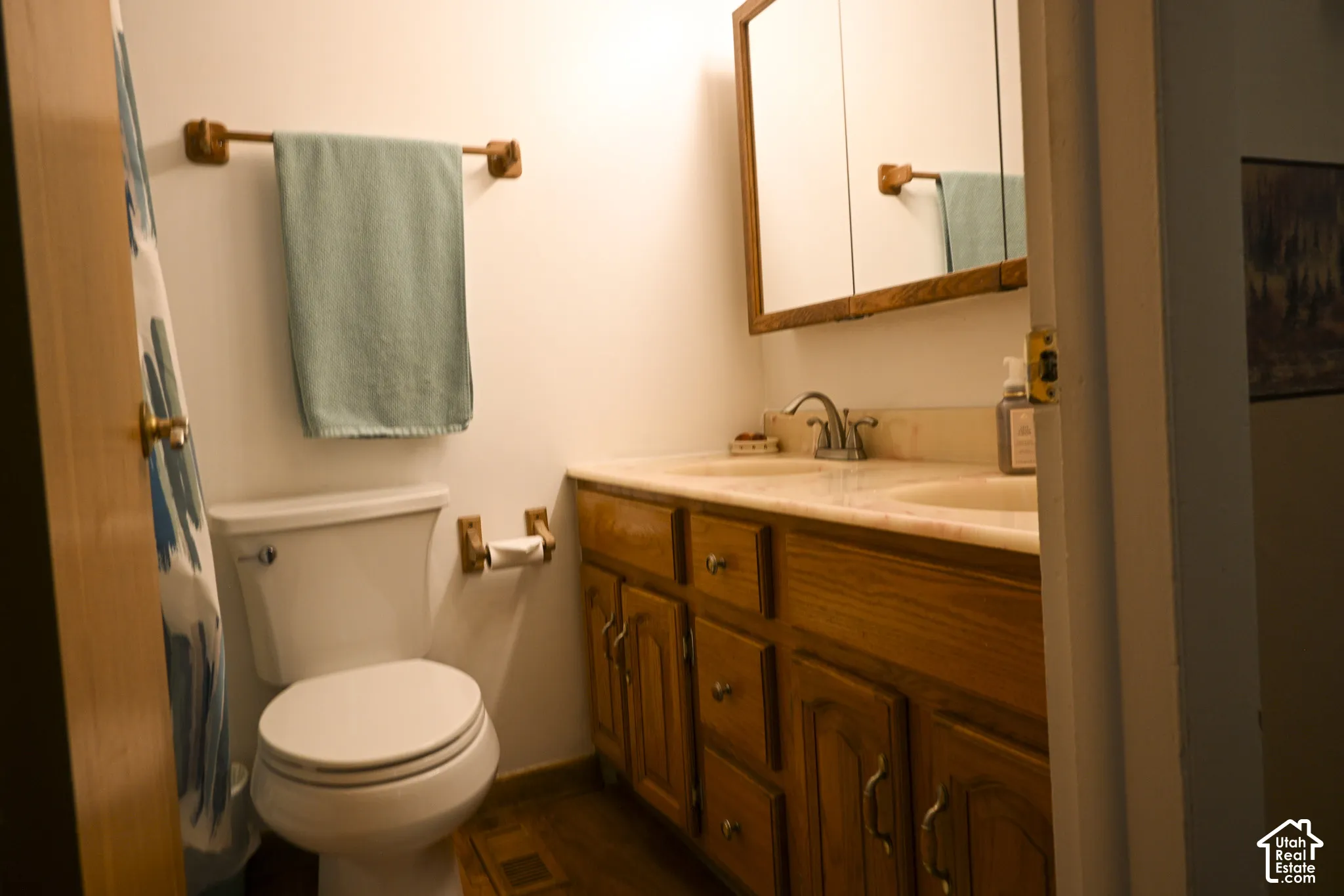 Bathroom featuring a double vanity with wood cabinetry, a dual-sink stone countertop, and a large wood-framed medicine cabinet