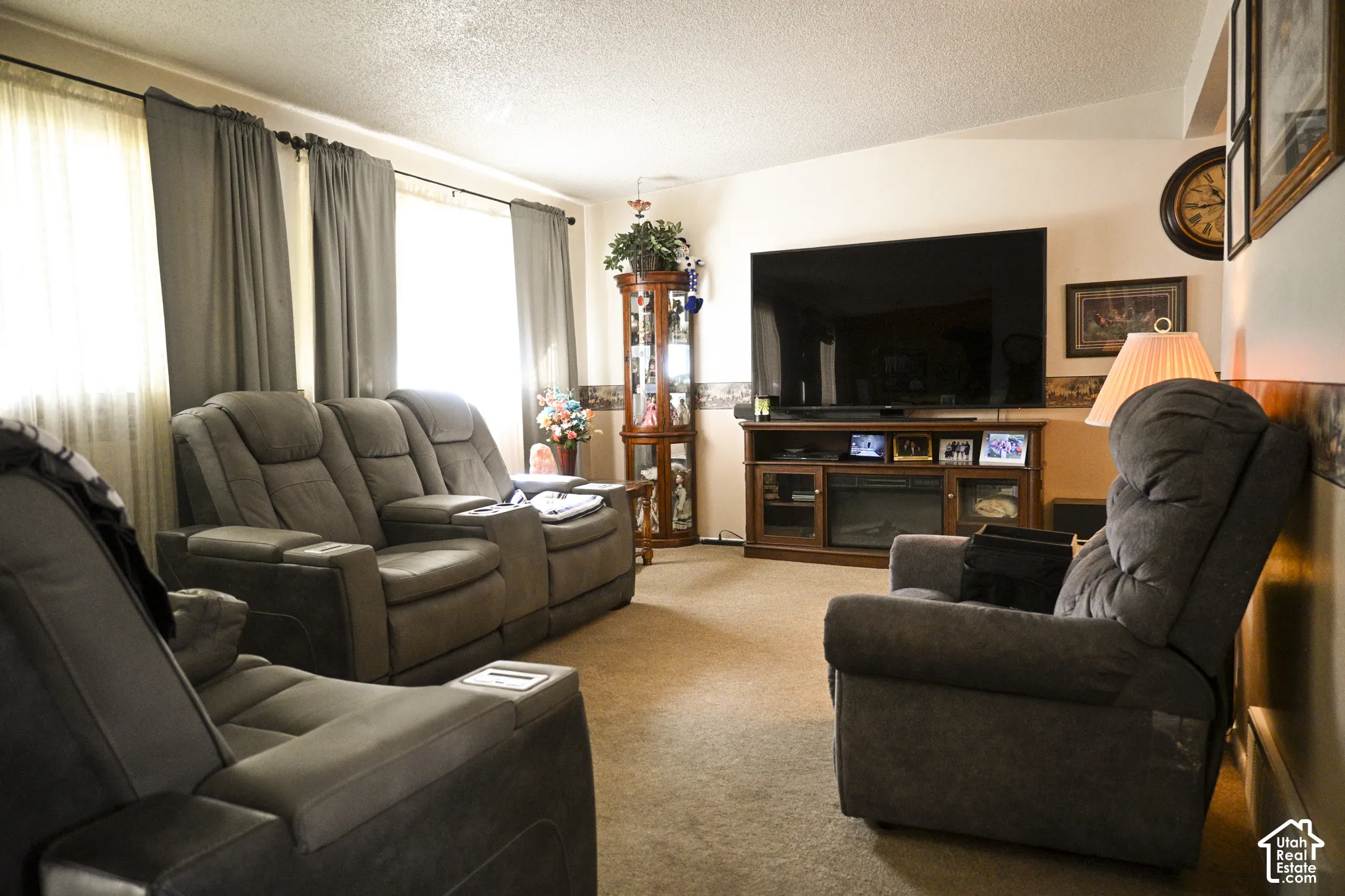 Living area featuring carpeted flooring, large windows, and a built-in media console with an integrated fireplace