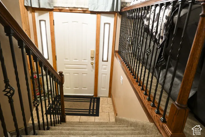 Entryway featuring a white paneled door with side lights, tile flooring, and a staircase with stained wood handrails and black metal balusters
