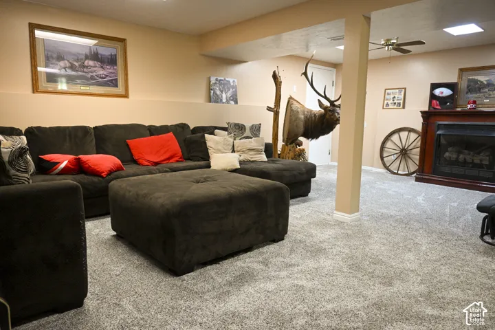Finished lower-level room featuring wall-to-wall carpeting, a fireplace with a wood-finish mantel, and a recessed ceiling fan